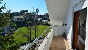 A balcony with a view of a residential area, including houses and greenery.