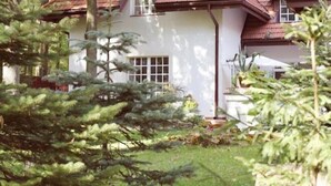 A house with a white exterior, a red roof, and a window with a white frame.