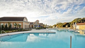 A large outdoor swimming pool with a clear sky and a building in the background.