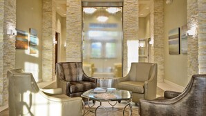 A spacious lobby with stone walls, leather armchairs, and a glass coffee table.
