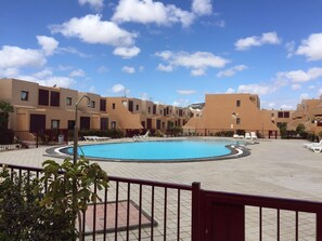 Une piscine entourée de bâtiments modernes, sous un ciel d’un bleu limpide.