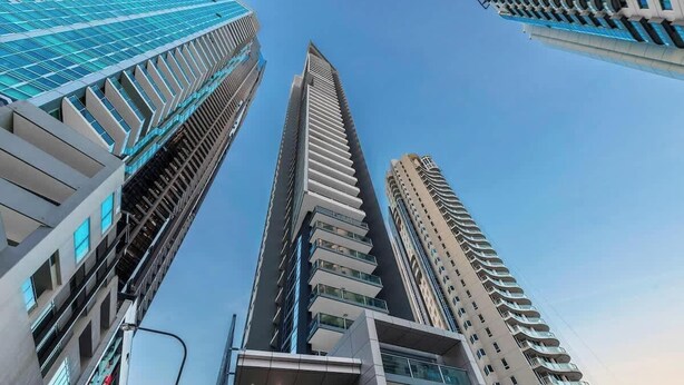 A modern high-rise building with a sleek, vertical design and large windows. - River & City Views | Premium Family Apartment (Brisbane City)
