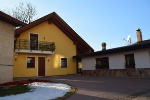 A yellow building with a balcony, a stone wall, and a chimney. - Cadorna Residence in Sonia (Tarvisio)