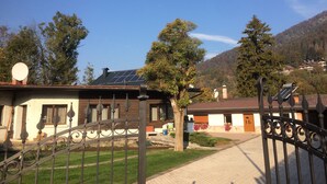 A residential area with a gated entrance, solar panels on a house, and a mountainous backdrop. - Cadorna Residence in Sonia (Tarvisio)