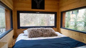 Ein gemütliches Blockhauszimmer mit einem Bett, einem Fenster und einer Holzzieldecke.