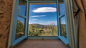 A room with an open window revealing a mountainous landscape and a clear sky. - Authentic stone built villetta with a magnificent view (Grižane)