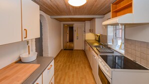 A narrow kitchen with wooden flooring, white cabinets, and a black stove. - 3 bedroom cozy home in Sydals (Sydals)