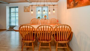 A dining area with a wooden table and chairs, overhead lighting, and a painting on the wall. - 3 bedroom cozy home in Sydals (Sydals)