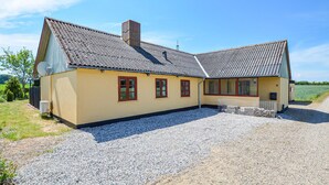 A two-story house with a sloped roof, a chimney, and a gravel driveway. - 3 bedroom cozy home in Sydals (Sydals)