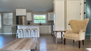 A modern kitchen with white cabinets, a stainless steel refrigerator, and a wooden dining table. - Wildwood on the lake, views, private dock, quiet cove, dog friendly  (Gainesville)