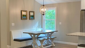 A modern kitchen with a dining area, a chandelier, and a window with a view of greenery. - Wildwood on the lake, views, private dock, quiet cove, dog friendly  (Gainesville)