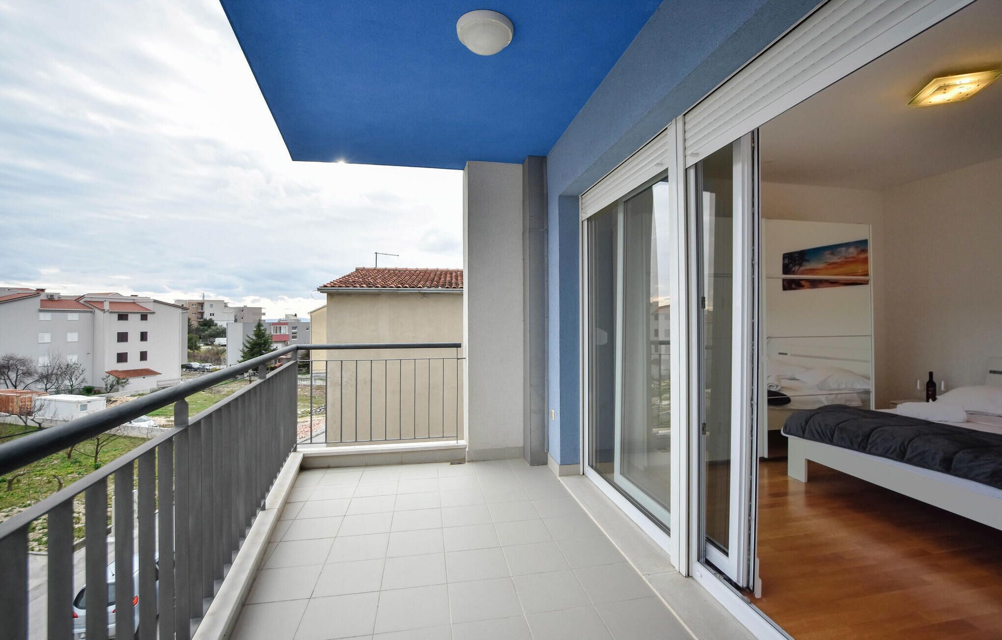 A balcony with a tiled floor, a railing, and a view of the surrounding buildings.