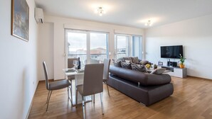 Un salon moderne comprenant un canapé, une table à manger, des chaises et un téléviseur.