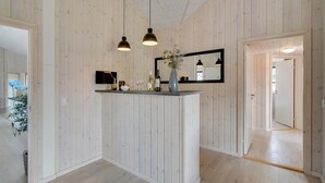 Ett modernt kök med träpanel, en köksö i mitten och hängande lampor.
