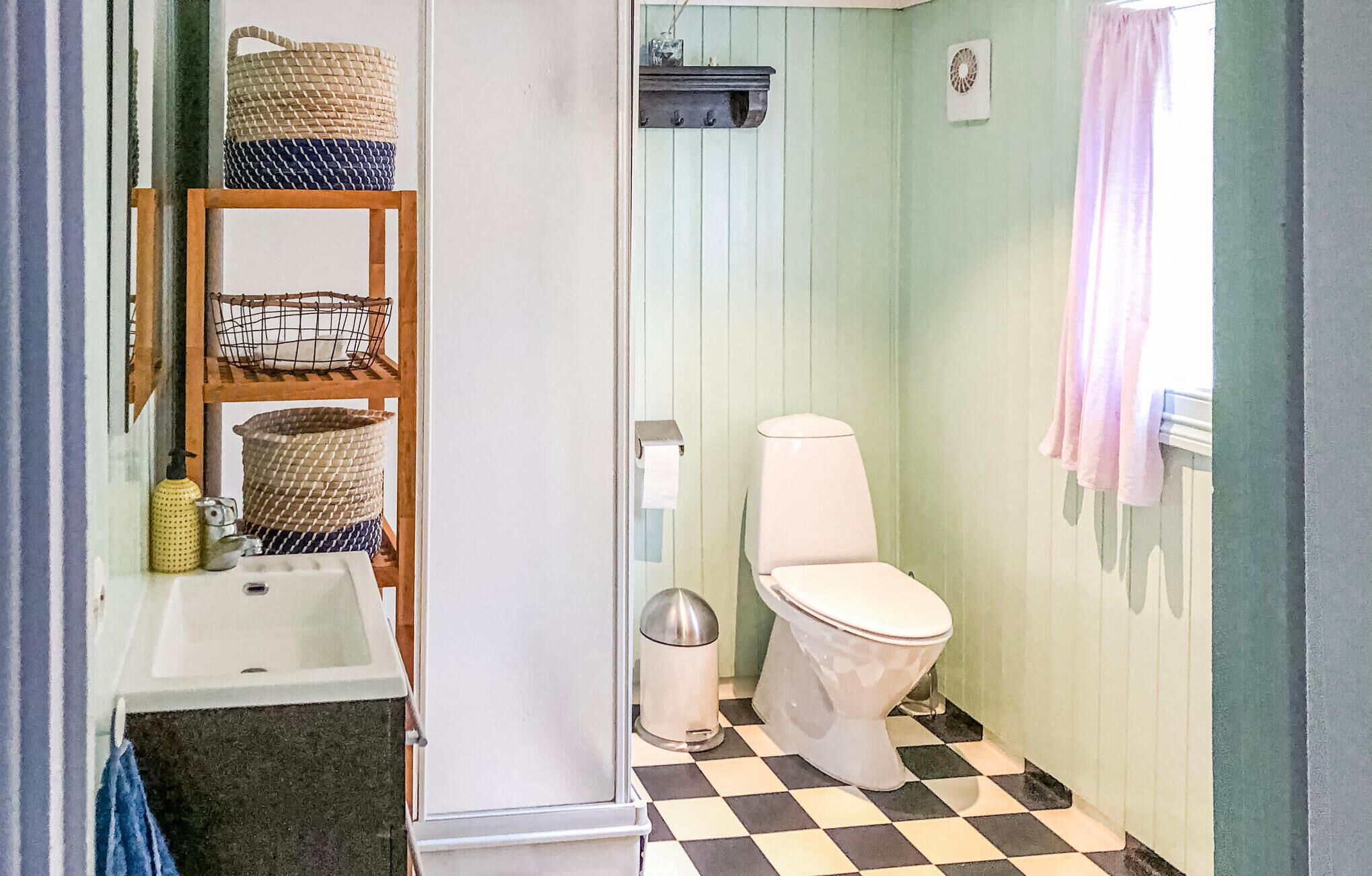 Une petite salle de bain comprenant des toilettes, un lavabo et une étagère avec des paniers.