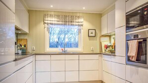 Een moderne keuken met witte kastjes, een raam met uitzicht op bomen en een Bosch oven.