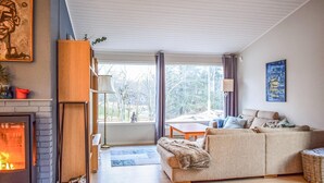 Een gezellige woonkamer met een open haard, een bank, een eettafel en uitzicht op de omgeving.
