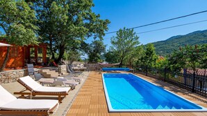 A poolside area with lounge chairs, a wooden deck, and a clear view of the surrounding landscape. - Nice home in Moscenicka Draga (Moscenicka Draga)