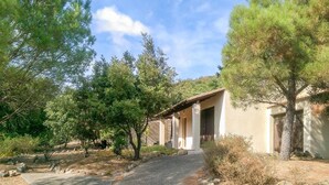 A building with a covered outdoor area, surrounded by trees and a gravel path. - Awesome home in Pierrerue (Pierrerue)