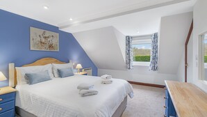 A bedroom with a bed, bedside tables, a window with curtains, and a painting on the wall.
