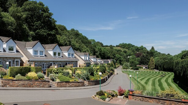 A row of townhouses with a well-maintained lawn and stone walls.