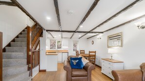 A spacious living area with a staircase, a kitchen, and a dining area.