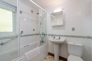 A bathroom with a glass-enclosed shower, a sink, and a toilet.
