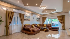 A spacious living area with a large L-shaped sofa, a coffee table, and a view of the outdoors through large windows. - Luxurious home in Dubrava kod Sibenika (Dubrava kod Sibenika)