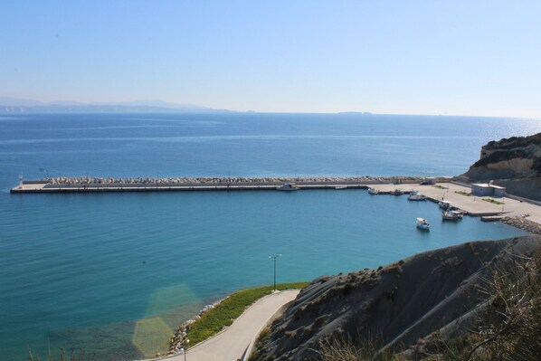 Un port de plaisance situé sur la côte, avec des bateaux amarrés, une jetée s’avançant dans l’eau et une vue dégagée sur la mer.
