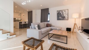 Een moderne woonkamer met een bank, salontafel en een eethoek met stoelen.