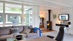Ett modernt vardagsrum med en soffa, ett soffbord, en öppen spis och en tv.