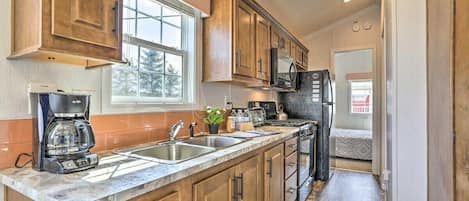 A kitchen with wooden cabinets, a stainless steel sink, a coffee maker, and a microwave.