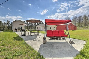 Un patio con un columpio, una mesa de picnic y mobiliario exterior.
