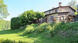 A stone house with a wooden fence, surrounded by lush greenery and a clear sky. - Beautiful apartment in villa for 6 guests with pool, WIFI, TV and patio (Molazzana)