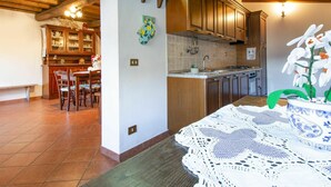 Una cucina con mobili in legno, zoccolo di piastrelle e zona pranzo con tavolo e sedie.