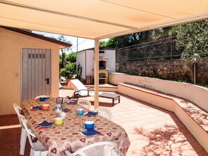 Eine Terrassengruppe mit Esstisch, Stühlen und einem überdachten Sitzbereich.