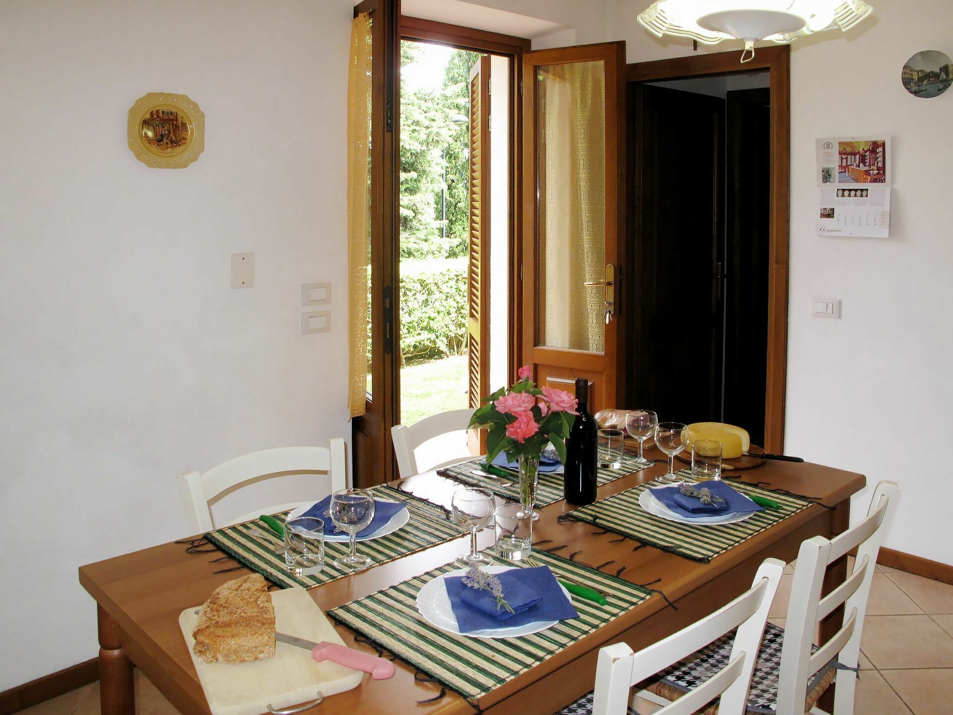 A dining table set with plates, glasses, and a bottle, with chairs around it.