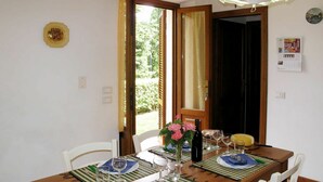 Une table à manger dressée avec des assiettes, des verres et une bouteille, entourée de chaises.