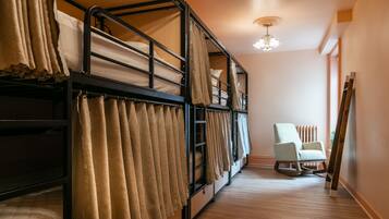 A bunk bed room with curtains, a rocking chair, and a radiator.