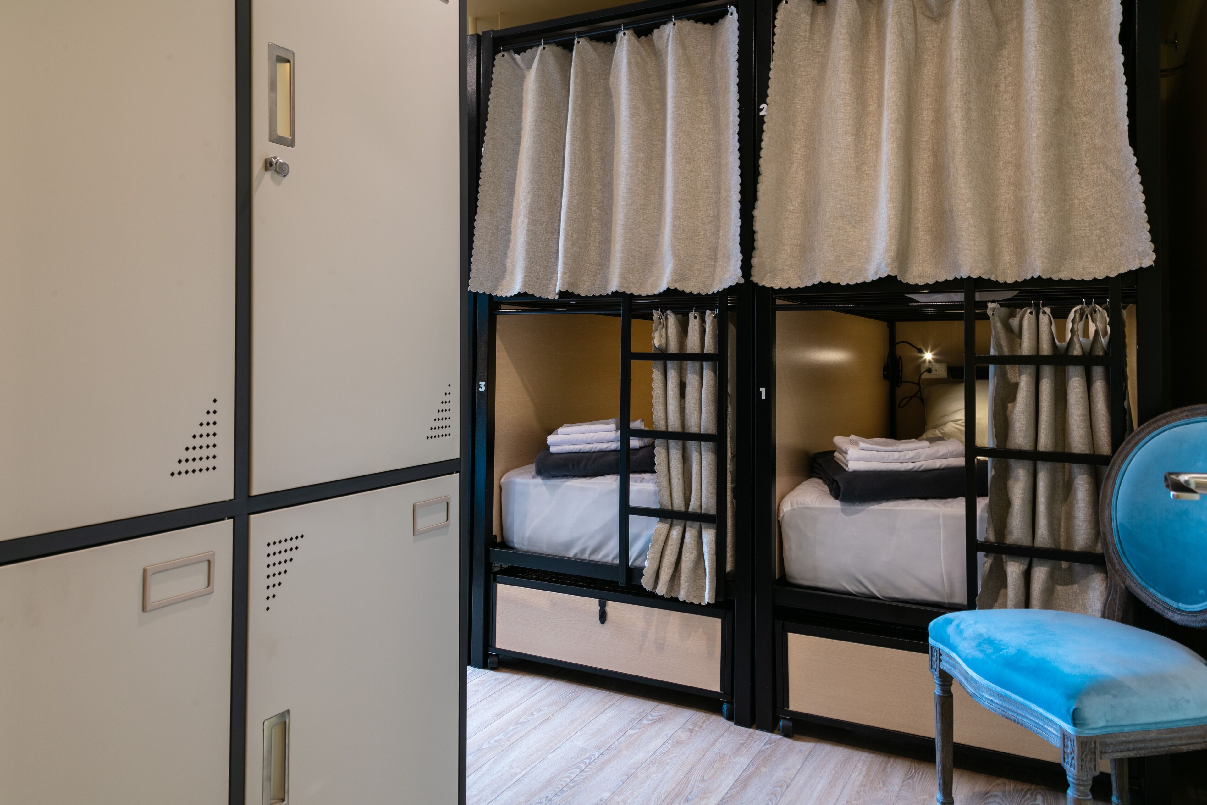 A room with bunk beds, a blue chair, and a wardrobe with multiple compartments.