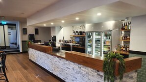 A bar area with a stone counter, seating, and a refrigerator stocked with beverages. - Empire Hotel Goulburn (Goulburn)