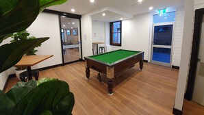 A pool table in a room with wooden flooring, a door, and a window. - Empire Hotel Goulburn (Goulburn)