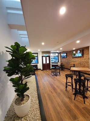 Un espacio interior moderno con suelo de madera, una planta en maceta y un televisor montado en la pared.