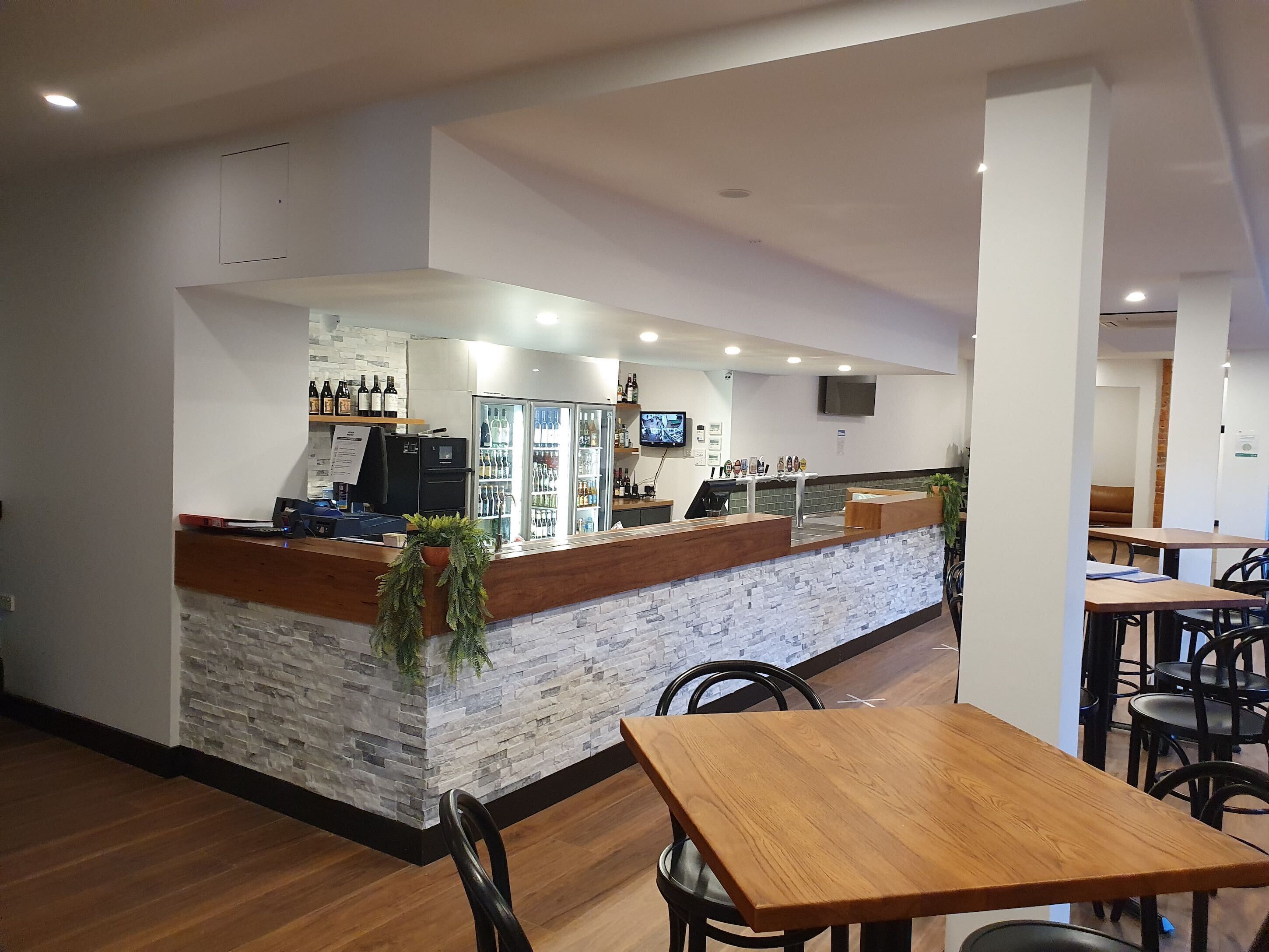 L'intérieur d'un café moderne, avec un comptoir en pierre, des tables et des chaises en bois.