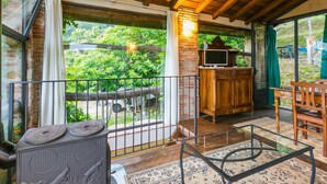 A cozy balcony with a rustic wooden ceiling, a TV, and a seating area with a table and chairs. - Cosy apartment for 2 guests with A/C, pool, WIFI, TV, patio and pets allowed (Pescia)