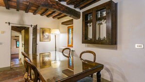 A dining area with a wooden table and chairs, a lamp, and a window with a view. - Lovely apartment for 4 guests with WIFI, pool, TV, patio and pets allowed (Pescia)