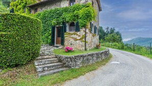 A stone house with ivy-covered walls, a wooden door, and a flower pot on the steps. - Lovely apartment for 7 guests with pool, WIFI, TV, patio and pets allowed (Pescia)