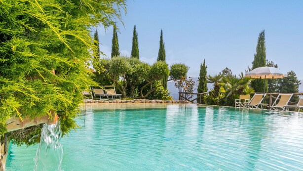 A clear swimming pool with lounge chairs and a waterfall feature. - Cosy apartment for 4 people with WIFI, pool, TV and patio (Pescia)