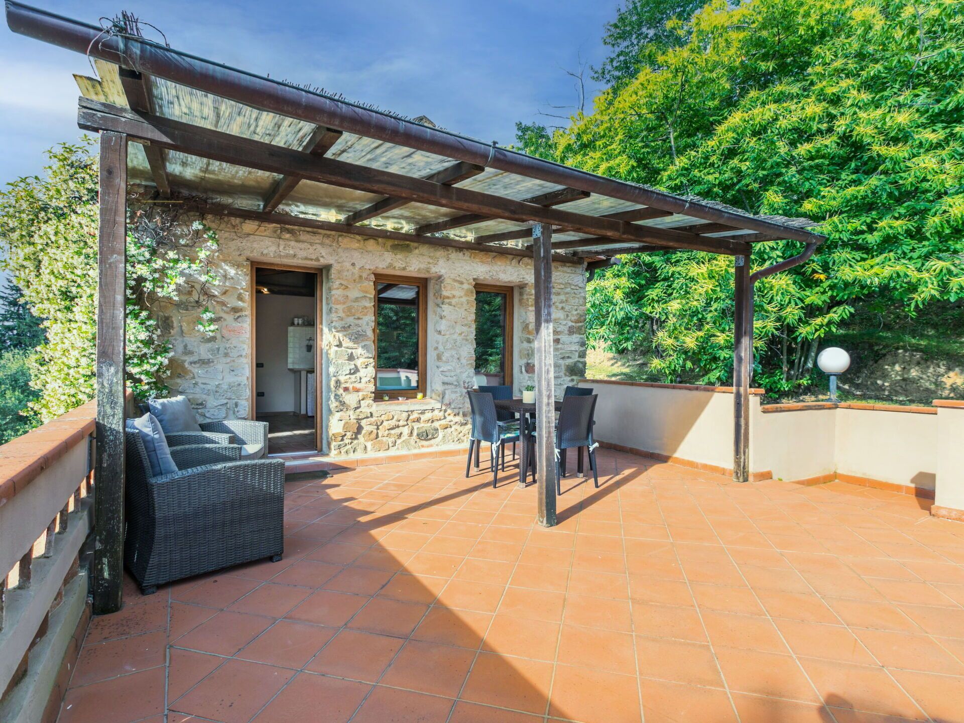 A stone building with a pergola patio, outdoor seating, and a view of greenery.