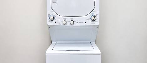 Une vue de face d’un lave-linge blanc, avec ses boutons de commande et sa porte.